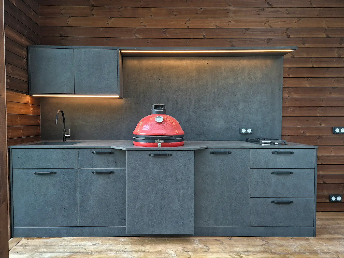 Outdoor kitchen with concrete-effect cabinets and a wooden wall on the terrace