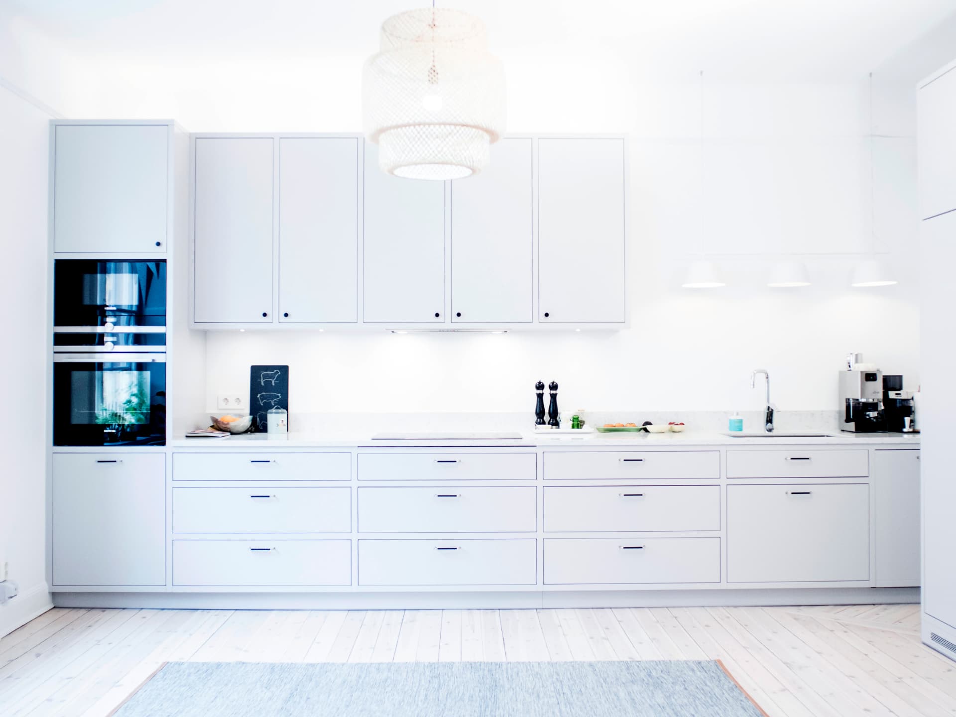 All-white streamlined kitchen with integrated appliances and rows of drawers
