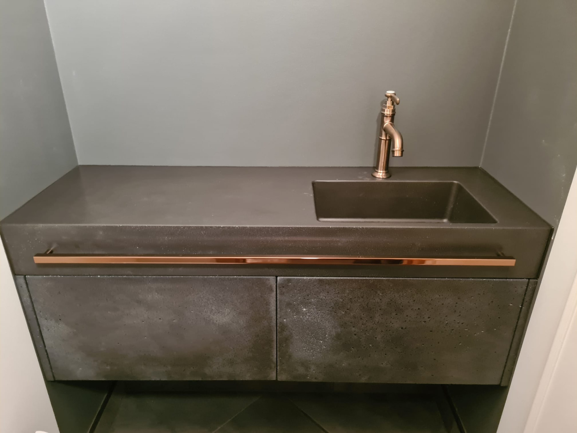 Dark concrete vanity unit with a brass fitting and a bronze tap