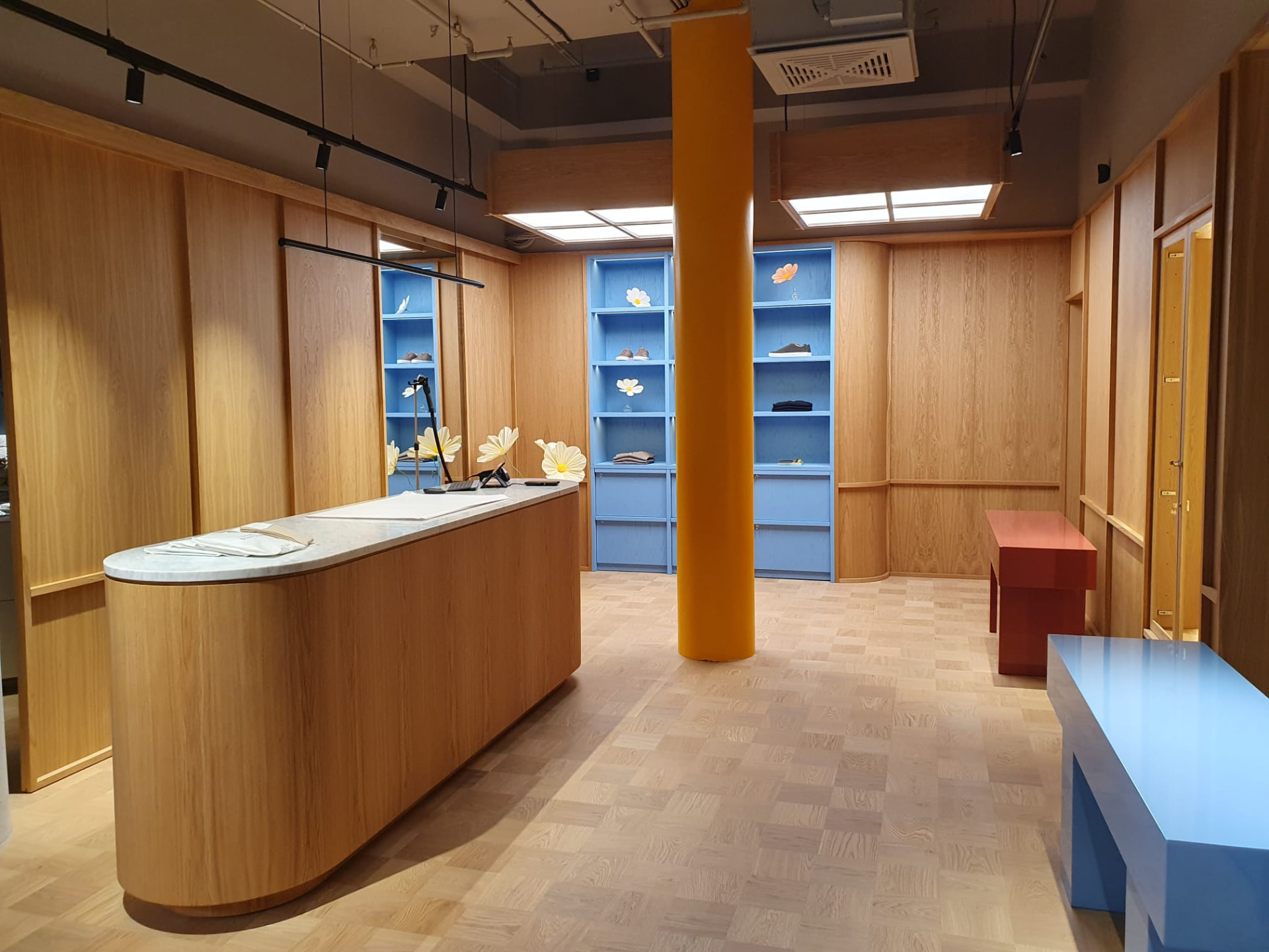 Butik med en rund disk i trä, blå hyllor och träpanelade väggar