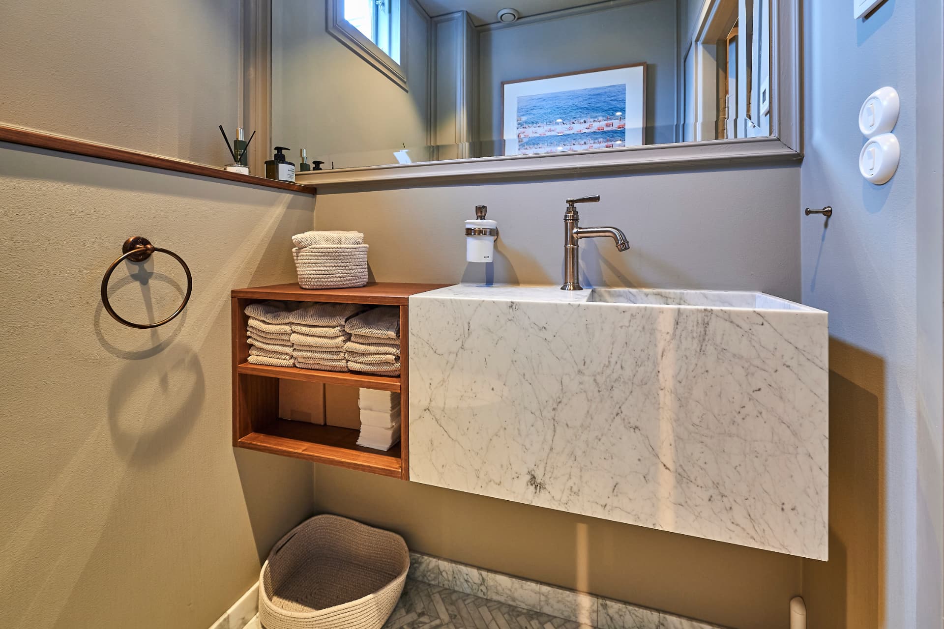 Marble sink with open wooden shelving and a towel ring
