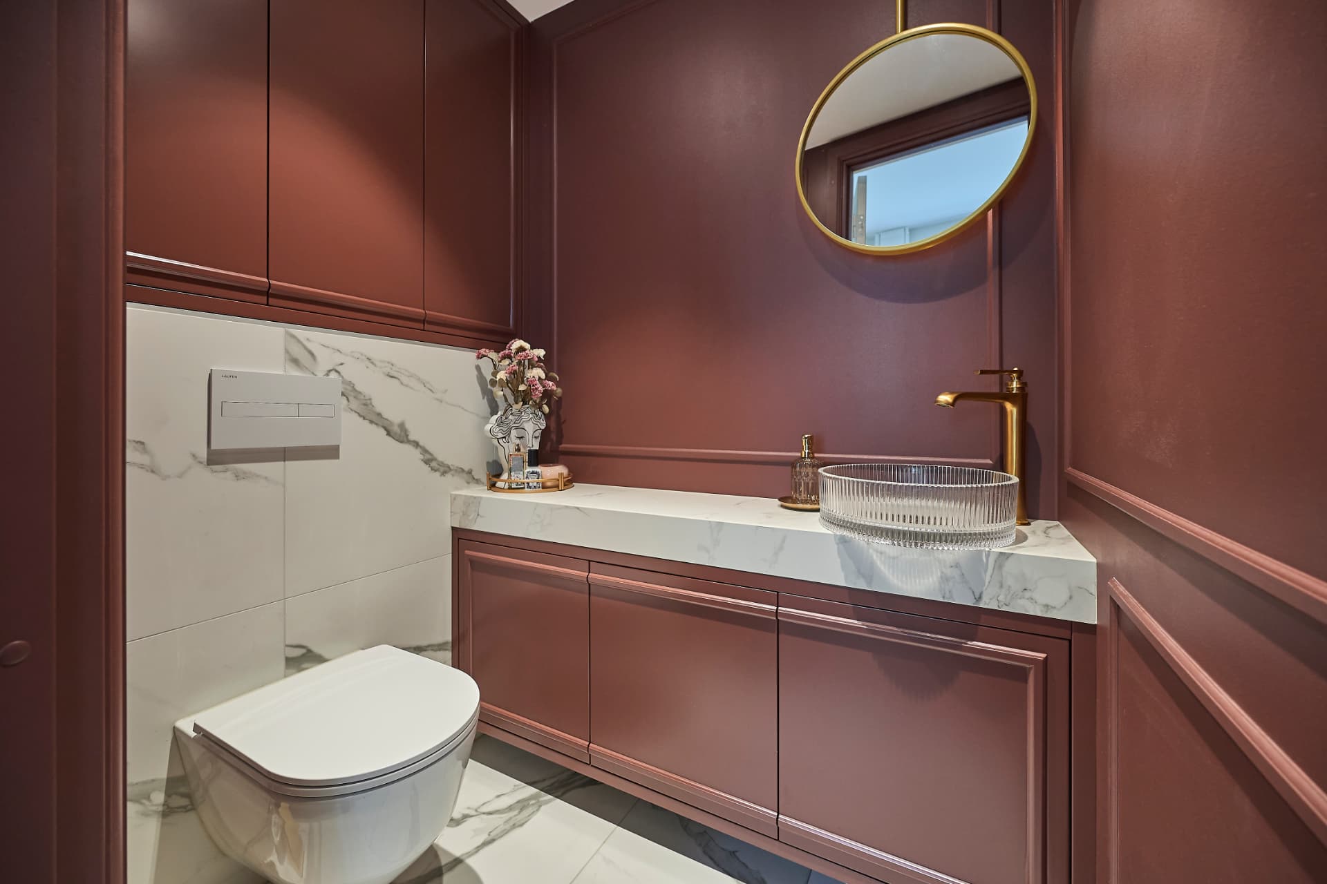 Bathroom with burgundy-toned walls, a marble-topped vanity unit and a round mirror