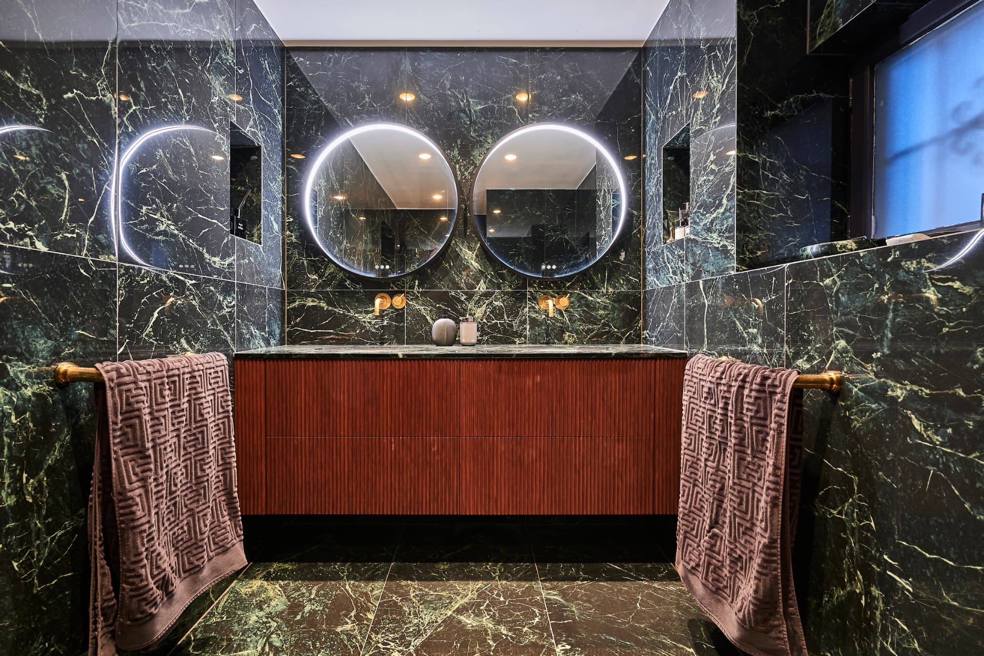 Bathroom with green marble and a wall-mounted wooden vanity unit with two illuminated mirrors