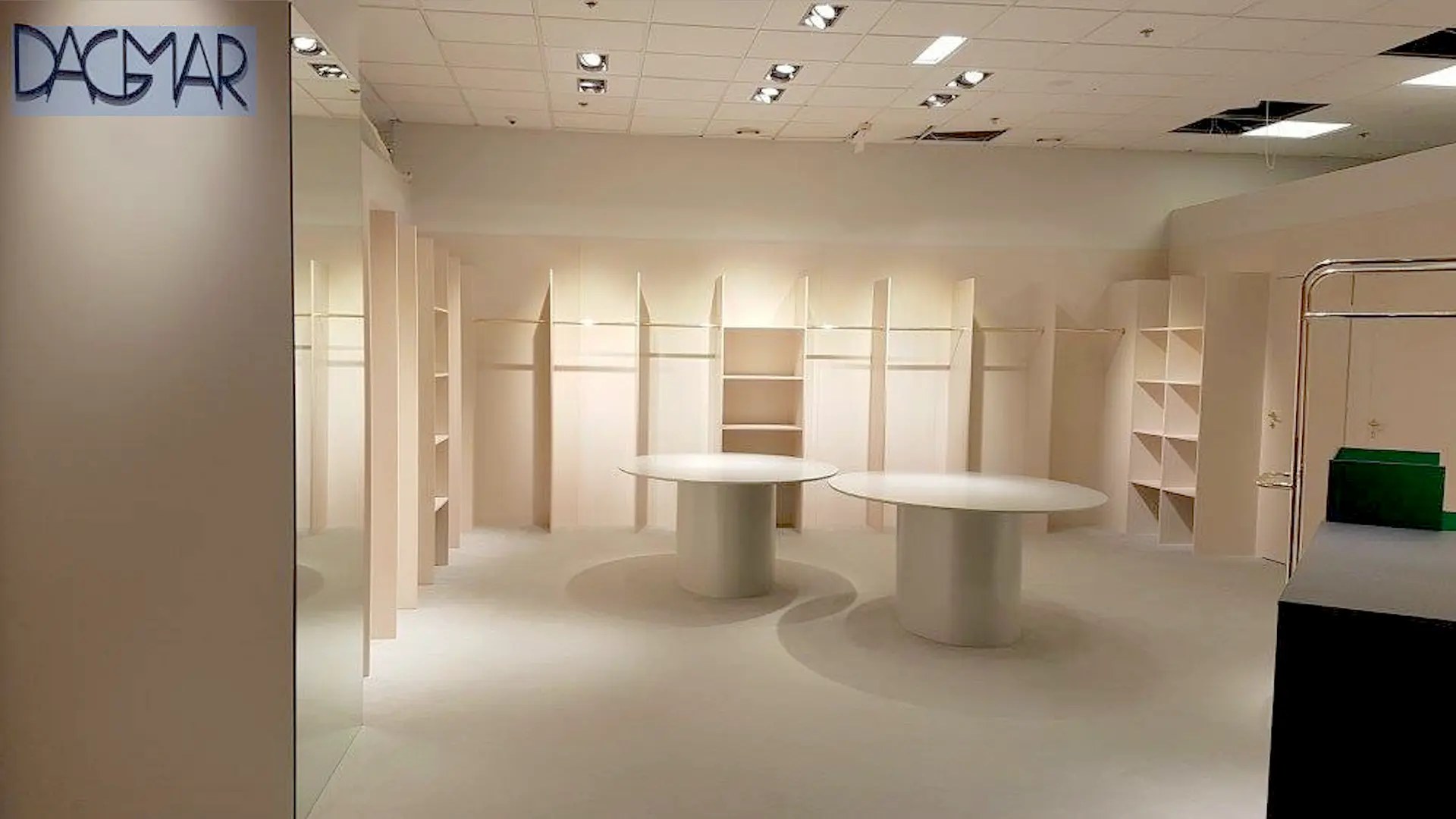 Ljus butik med väggmonterade hyllor och runda utställningsbord